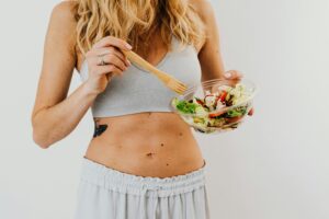 Diet, Young woman in sports attire holding a fresh salad bowl, promoting a healthy lifestyle.