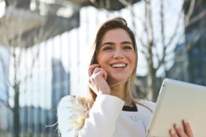 Joyful mind,Confident businesswoman using her tablet and phone, smiling outdoors in sunlight.