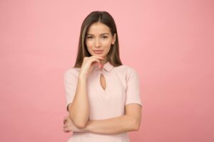 adhd Portrait of a young woman posing elegantly in a studio with a pink background.