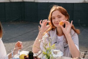 food, diet Smiling young woman enjoys a casual brunch outdoors, holding snacks and surrounded by friends.